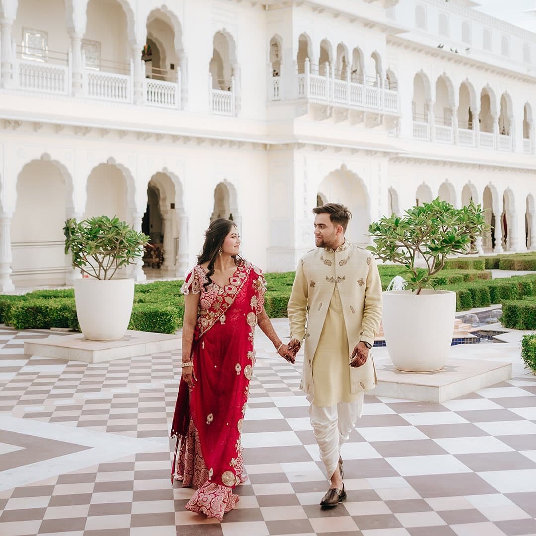 A couple walking hand in hand together through a palace courtyard