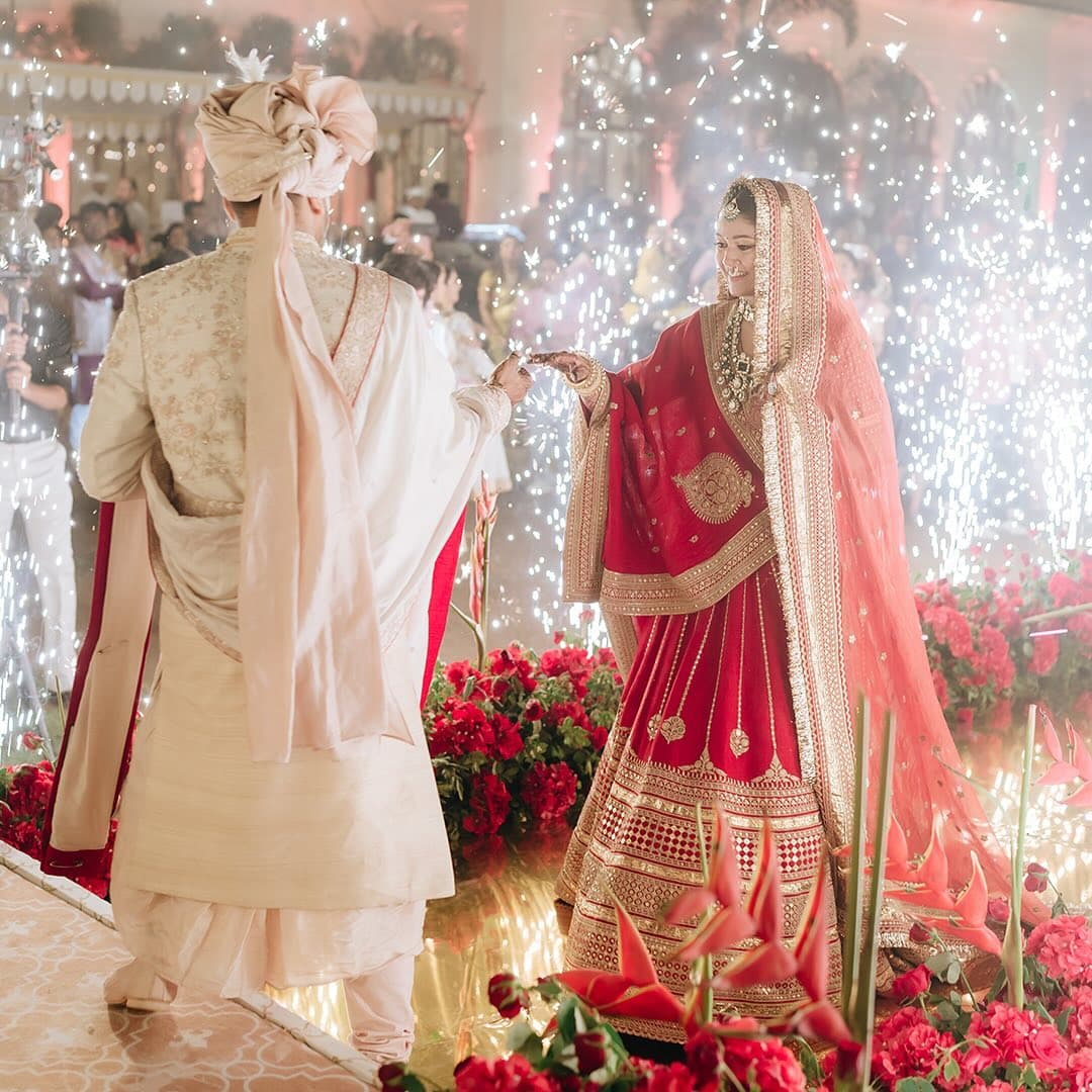 A bride and groom during their ceremony, framed by sparklers